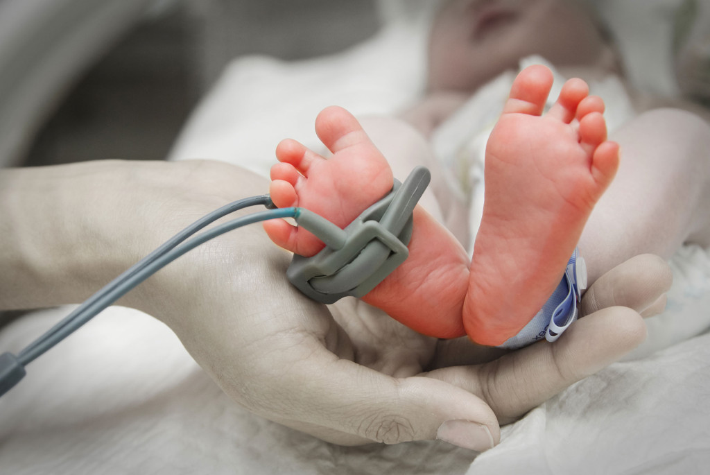 childs feet held in adult hand with pule monitor 